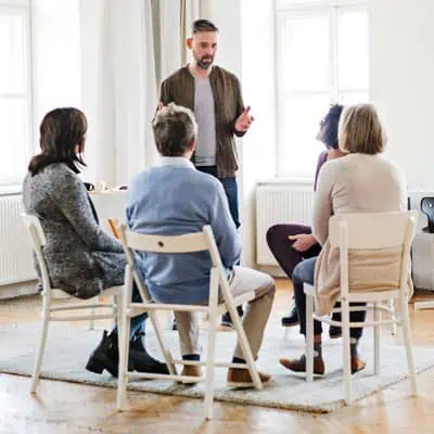 Canva-A-Man-Talking-to-Other-People-during-Group-Therapy-1 Men and women engaging in a meth addiction treatment session.